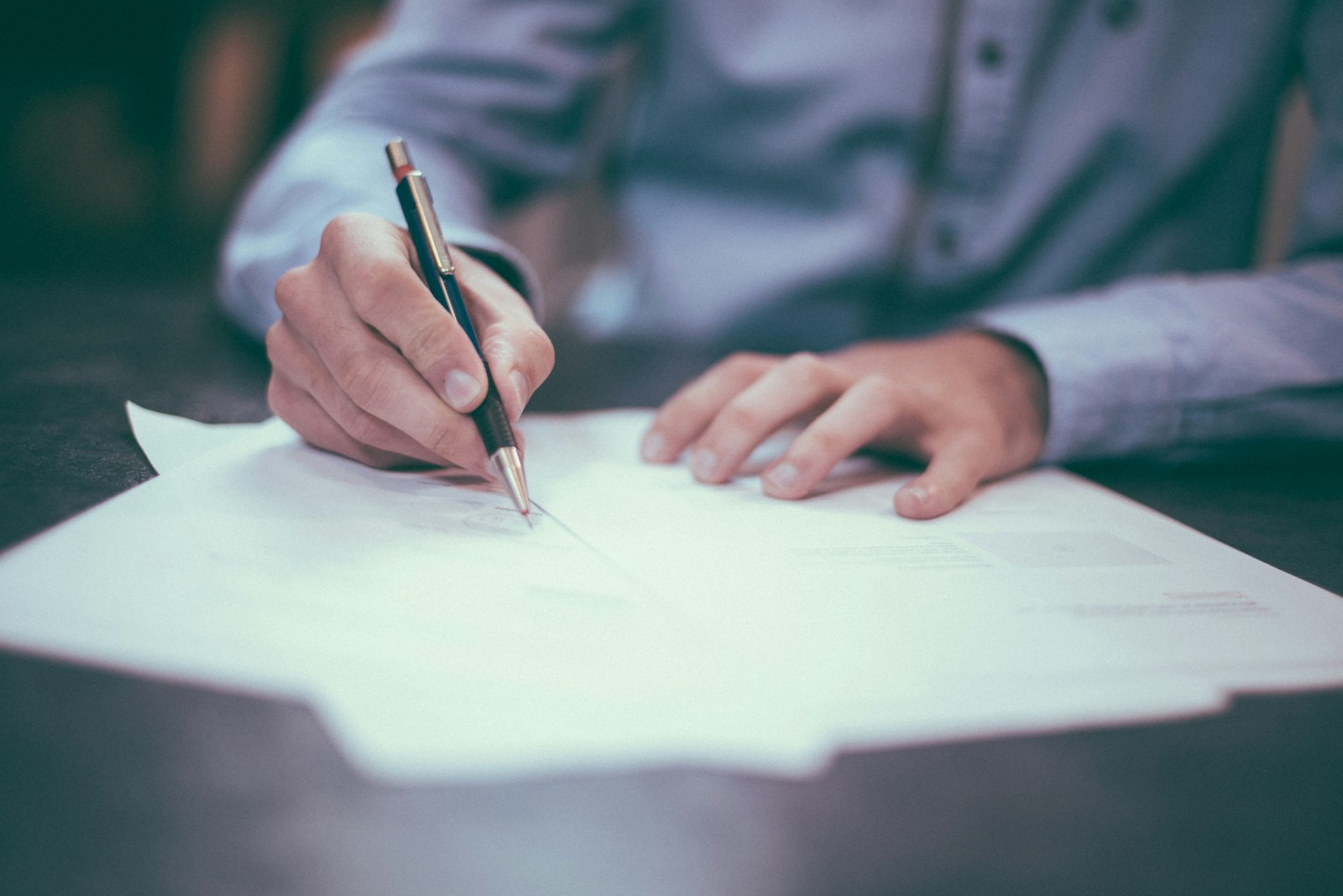 Hand met pen boven documenten die worden nagekeken