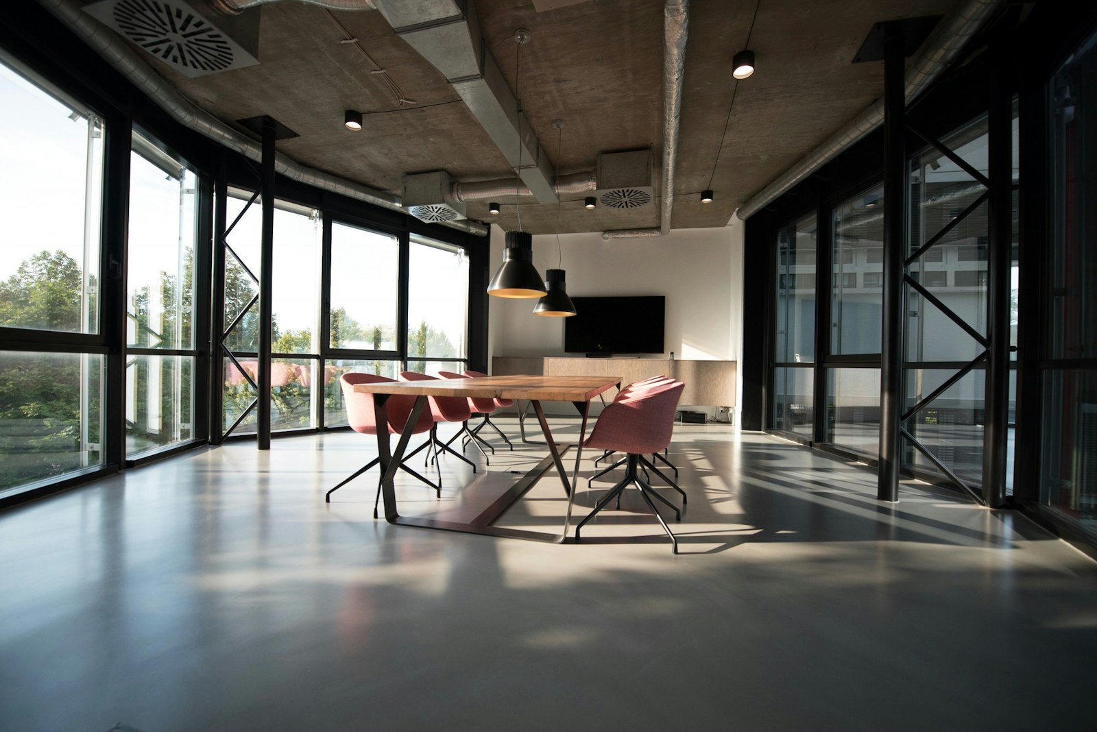 Lege vergaderzaal met houten tafel en roze stoelen