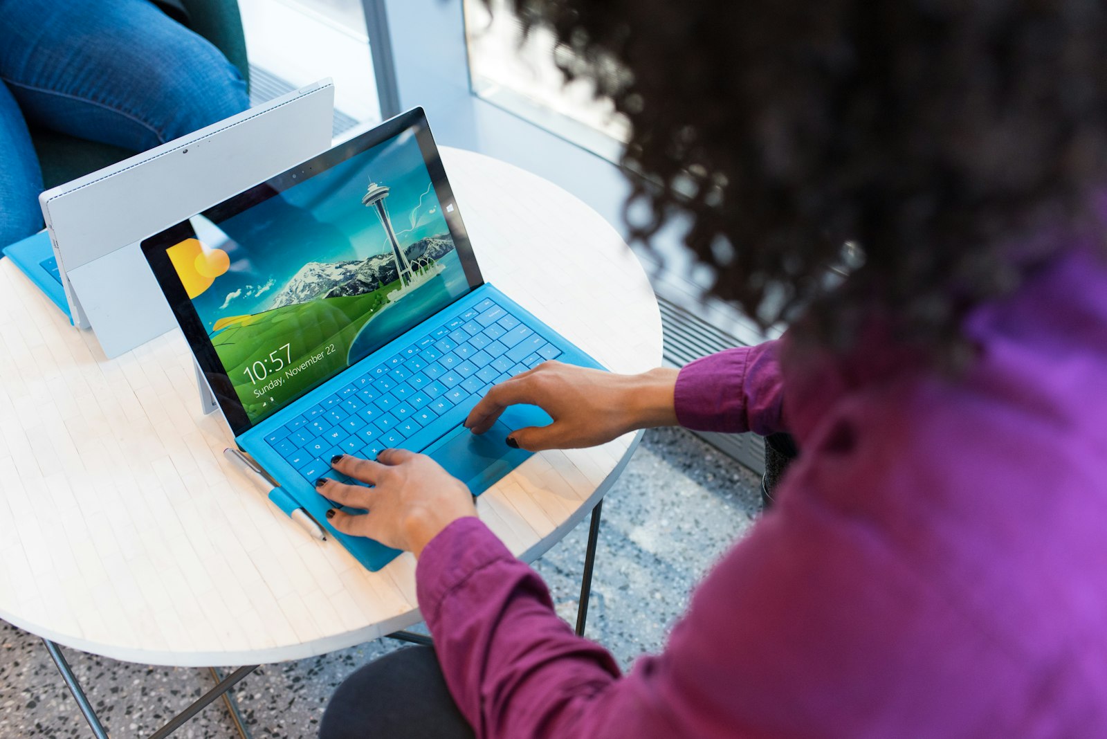 Persoon die op een laptop werkt aan een ronde tafel